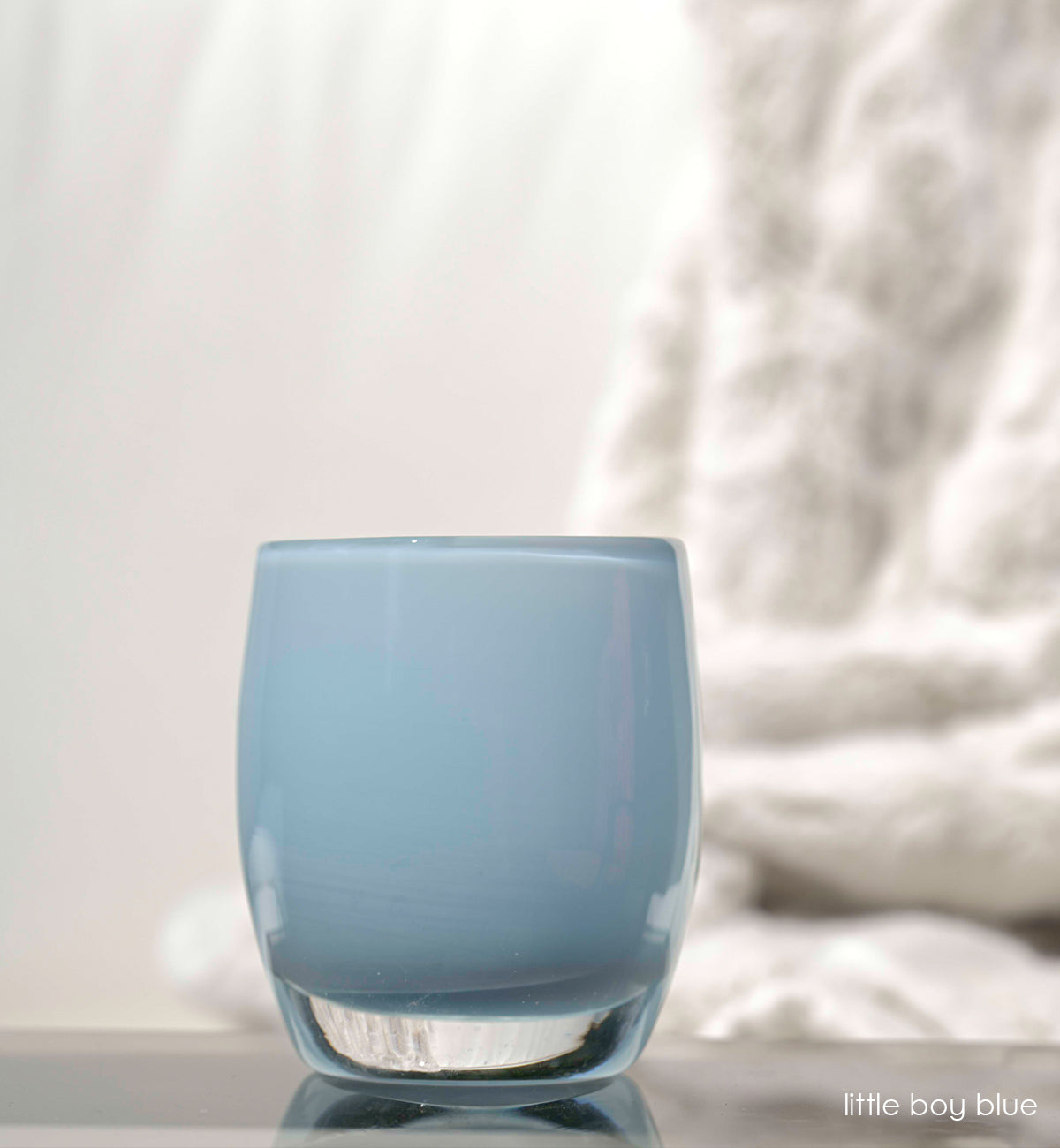 little boy blue, soft blue hand-blown glass votive candle holder with white in background.