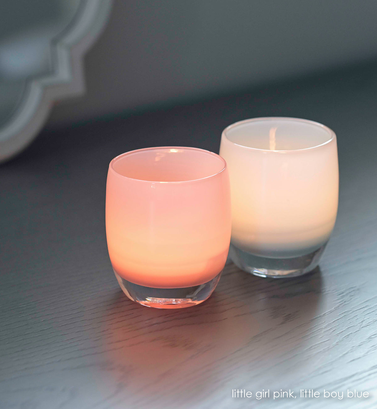 little girl pink, soft pink hand-blown glass votive candle holder. Paired with little boy blue on a gray wood surface.