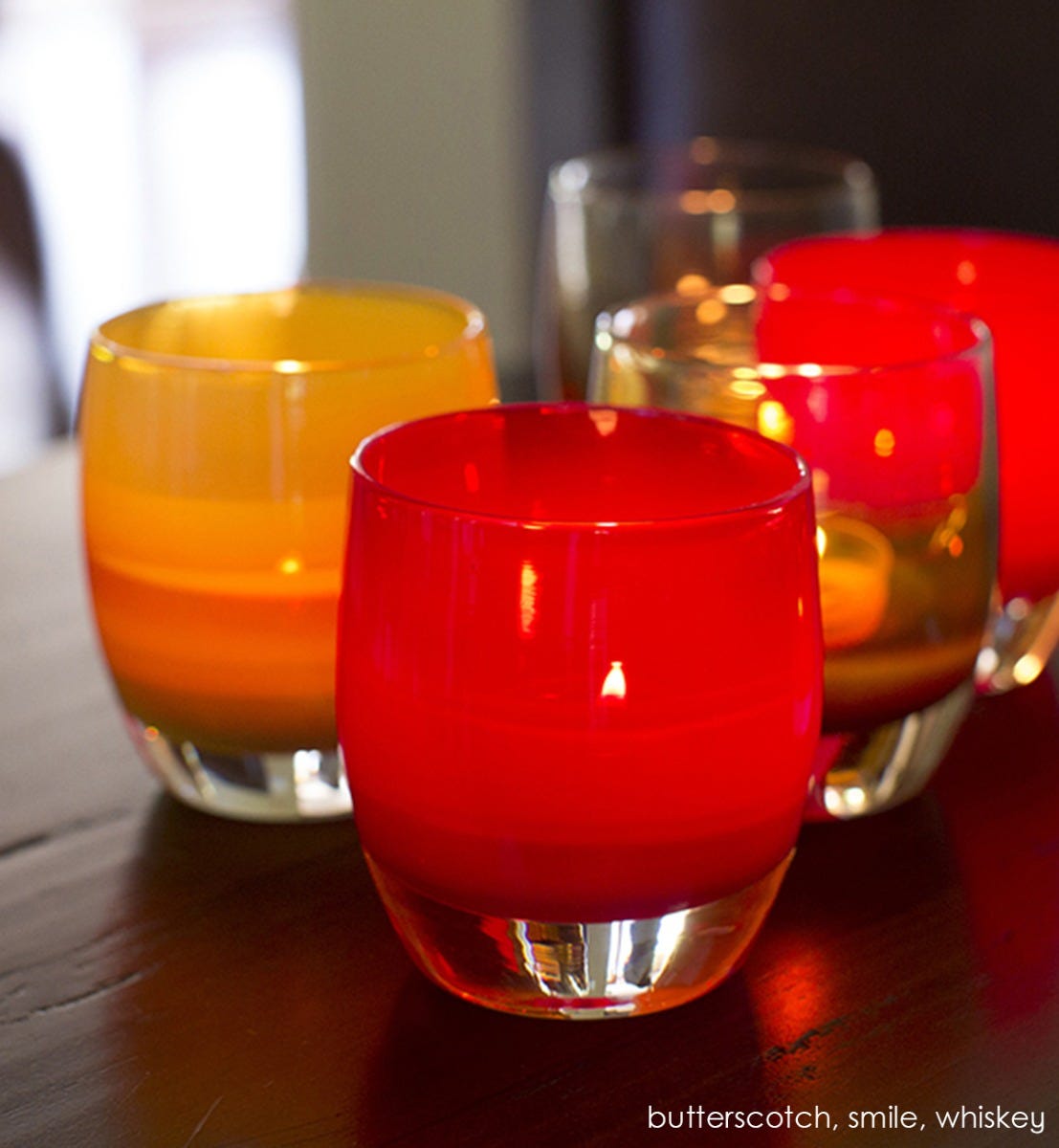 smile translucent bold red hand-blown glass votive candle holder. Paired with butterscotch and whiskey.