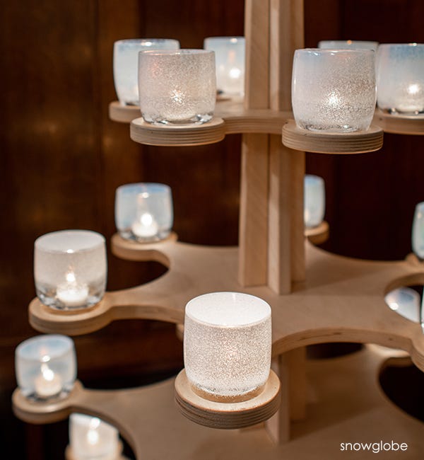 several snowglobe hand-blown white frosted glass votive candle holders on a wood glassybaby tree.