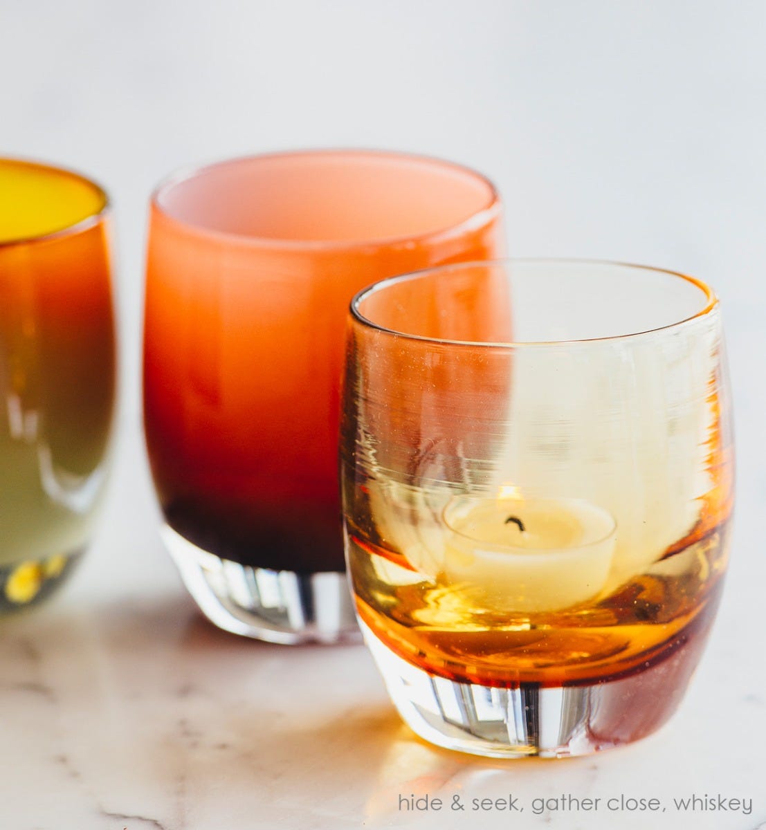 whiskey, transparent light amber, hand-blown glass votive candle holder. Paired with hide and seek and gather close on a marble surface.