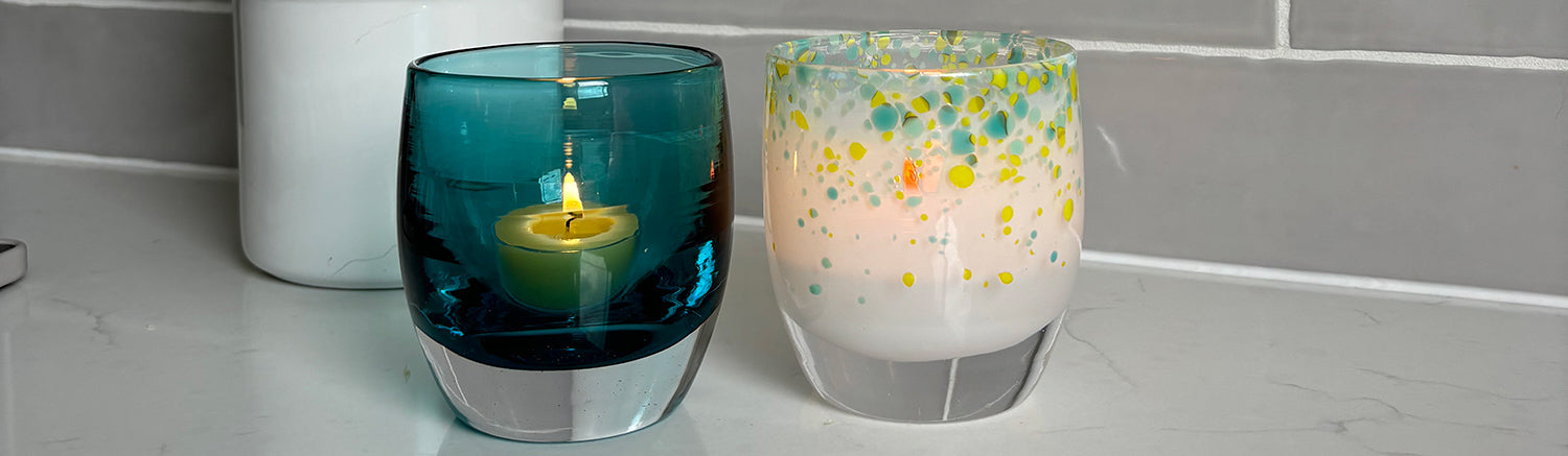 night out and friday night, a beautiful pairing of hand-blown glass votive candle holders sitting with lit tealights on a kitchen counter.