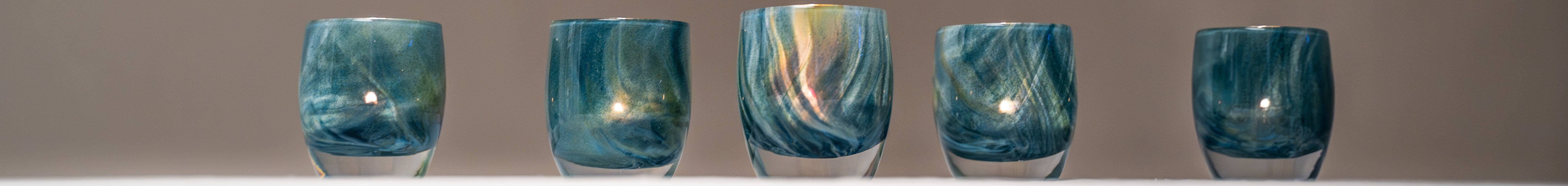 heavenly, exotic blue green swirl, hand-blown glass votive candle holders on a table with white table cloth.