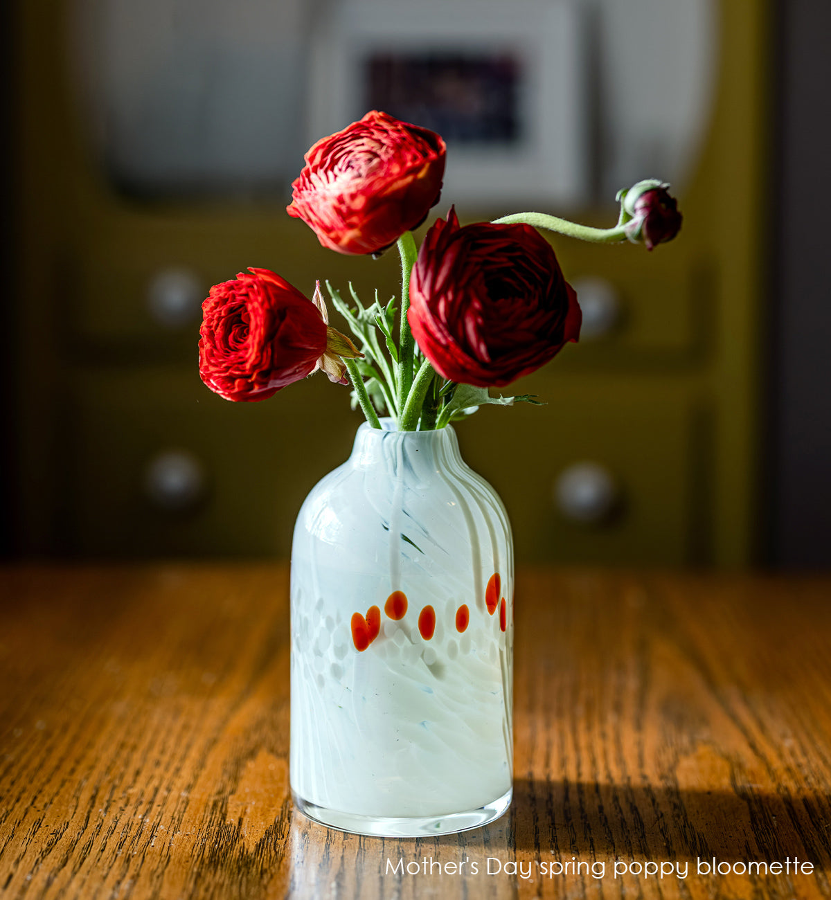 white bloomette vase with red spots with red flowers on wood table