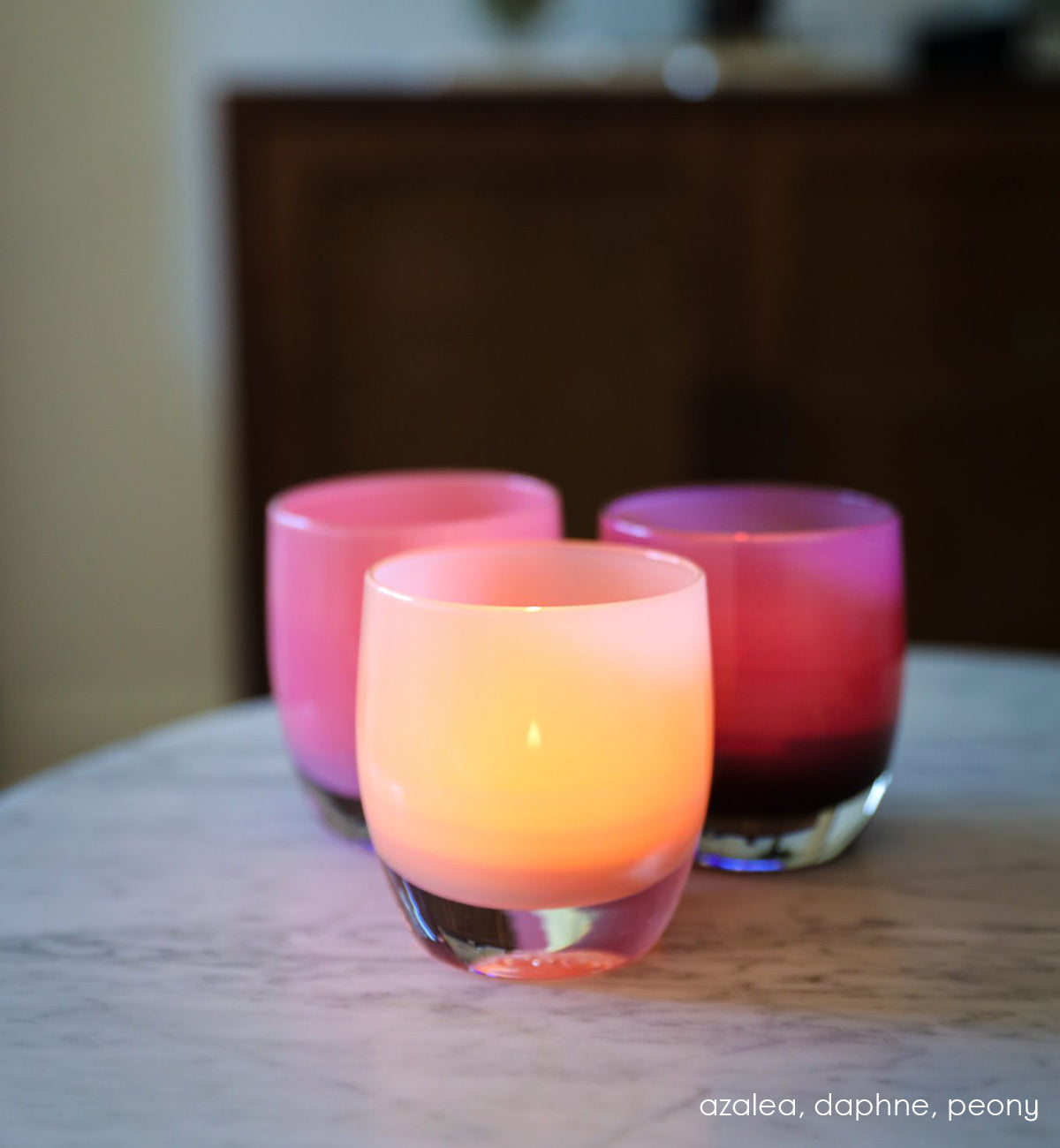 azalea light pink hand-blown glass votive candle holder on a marble counter with daphne and peony.