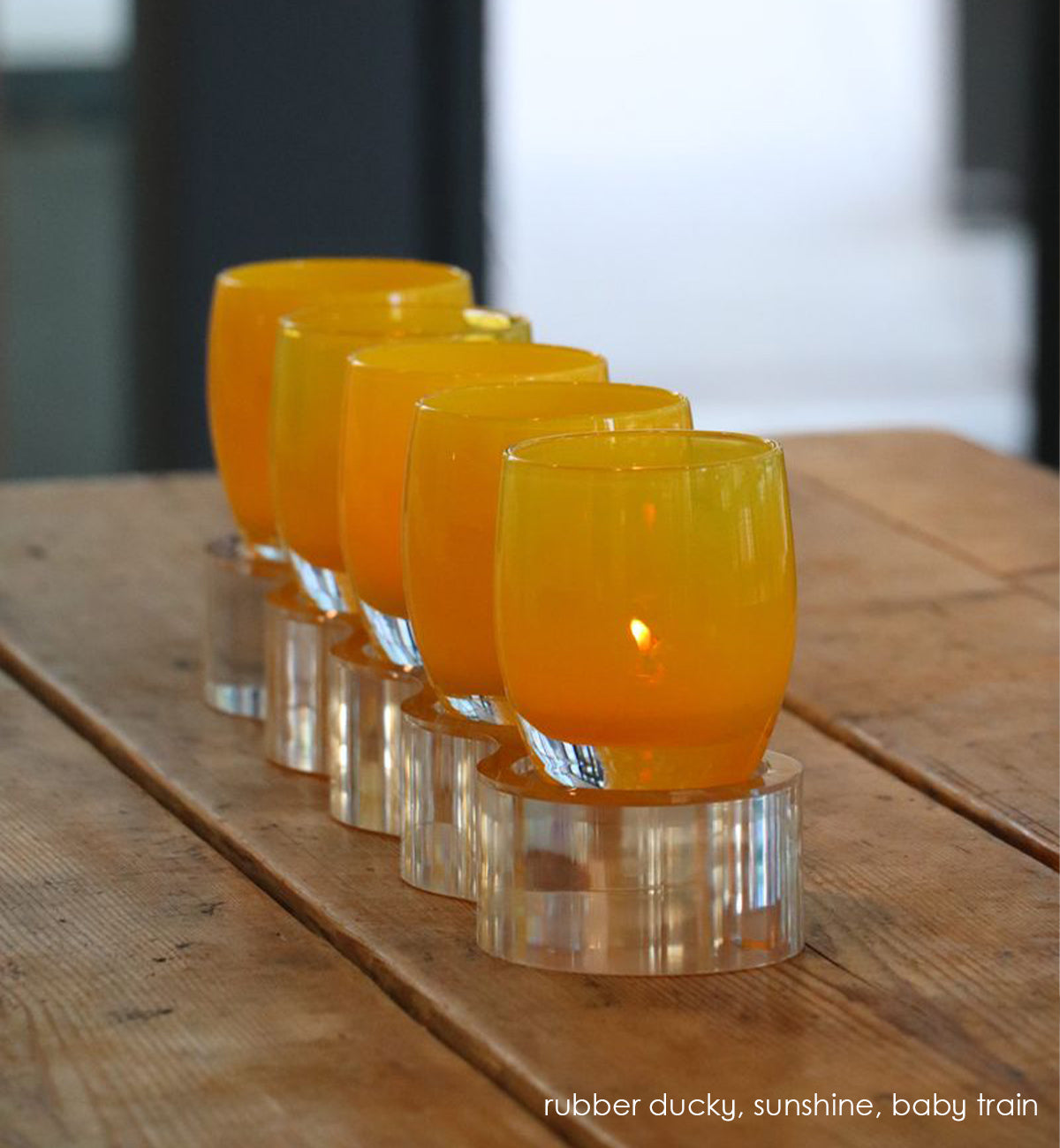 5 well acrylic baby train holding rubber ducky and sunshine on wood picnic table.