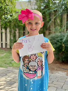 a young girl battling cancer, holding up a hand-made sign that reads 'Thank You B+' for The B+ Foundation