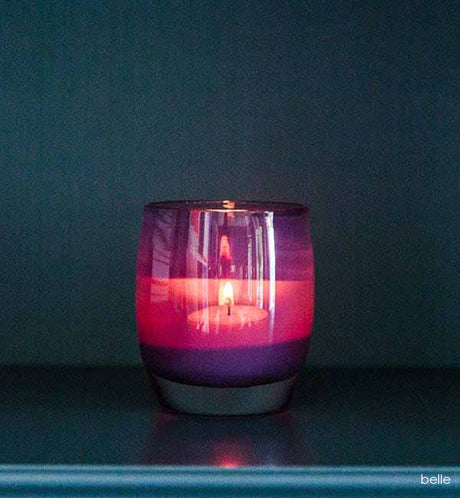 belle regal purple hand-blown glass votive candle holder, on a blue bookshelf.