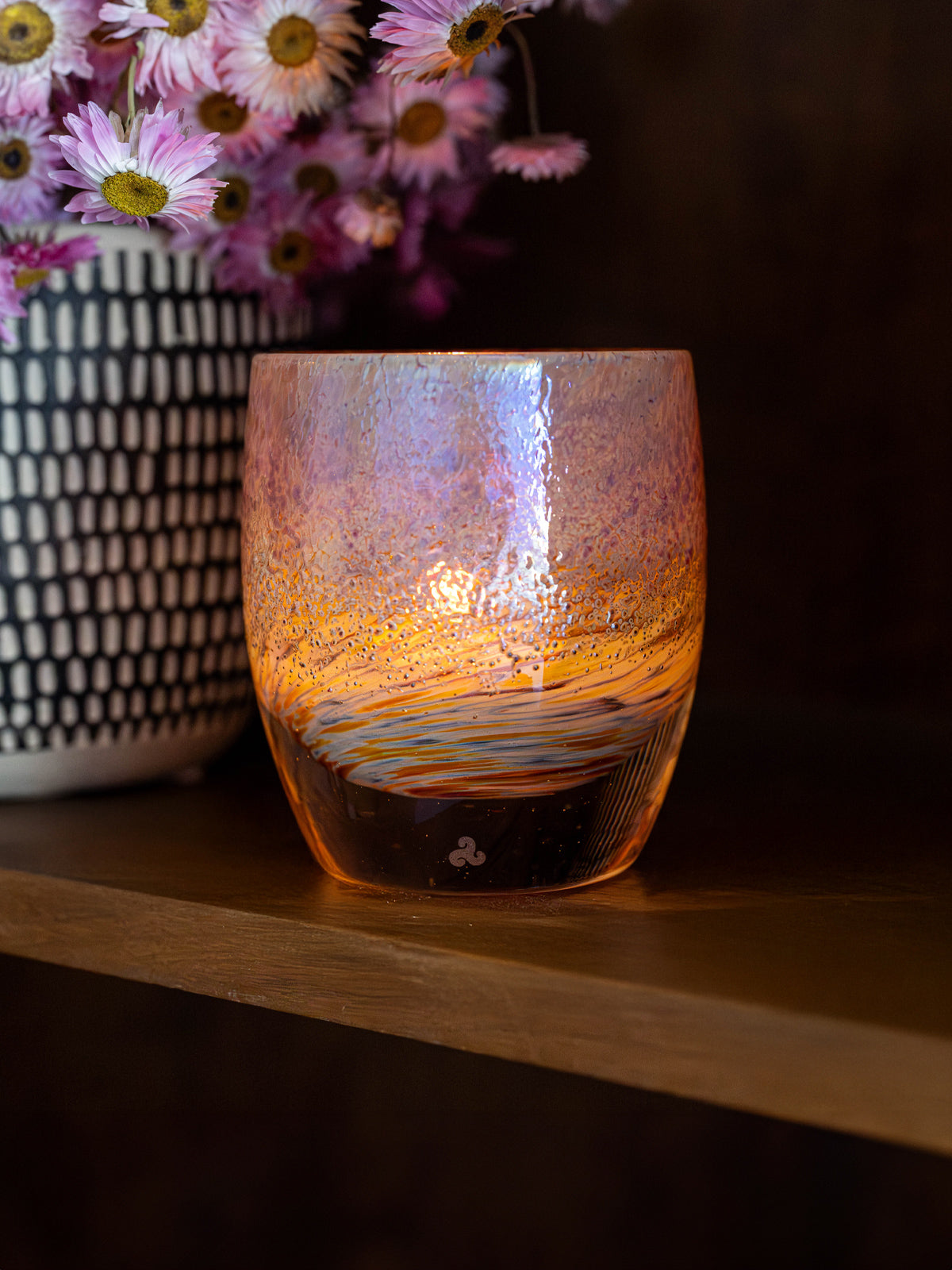 blaze of glory votive candle holder opaque with swirls of orange, blue and purple on a wooden shelf