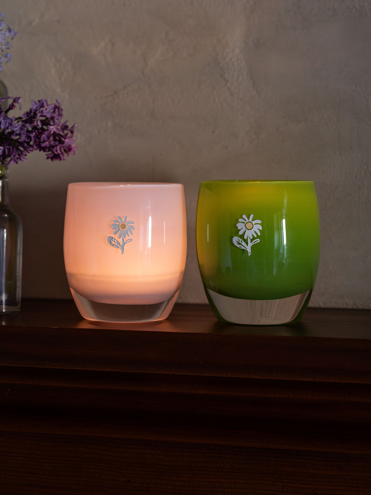 glassybaby bloom collection pink and green glassybaby with white glowers engraved on them.