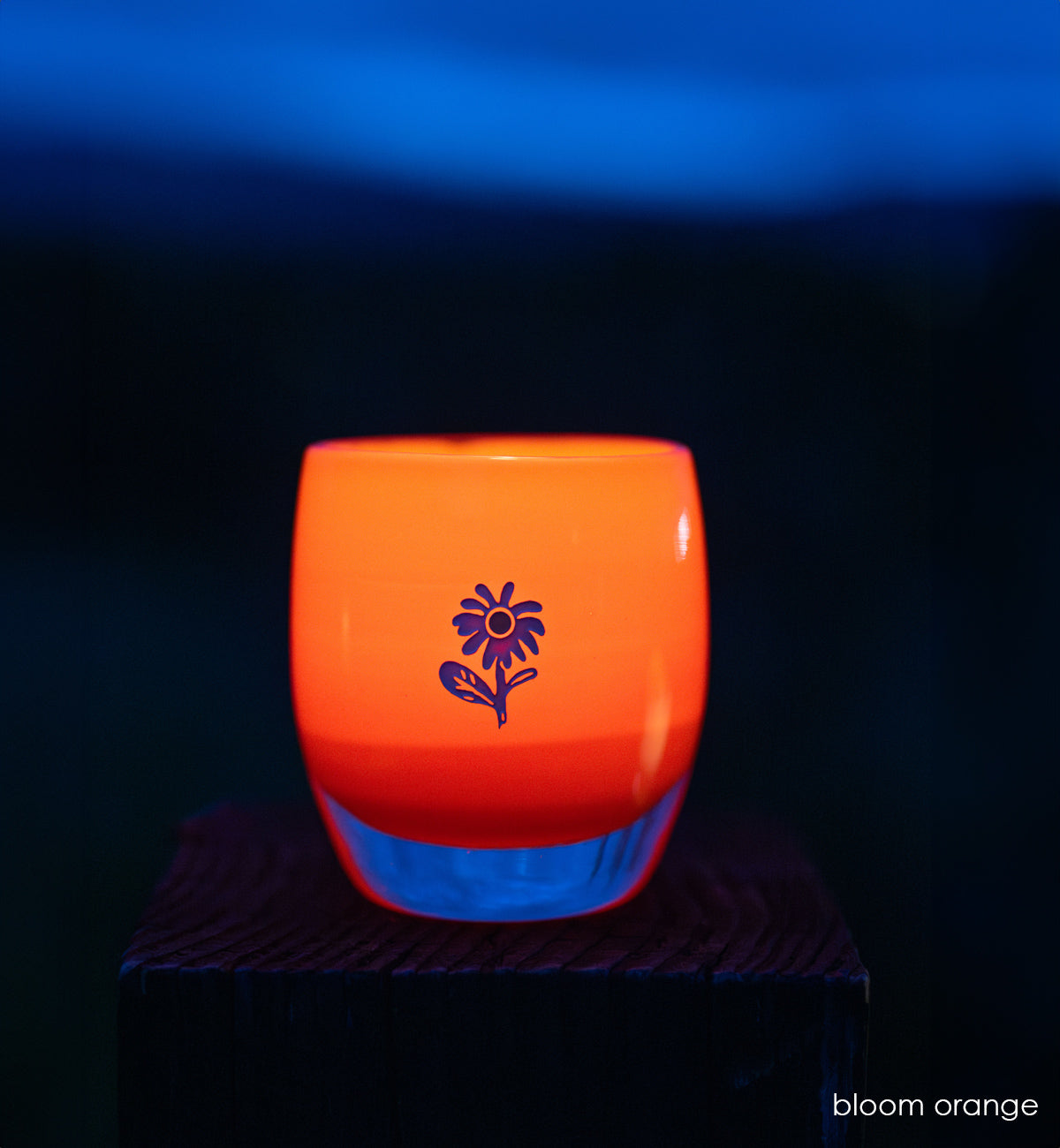 bloom orange glassybaby with white flower etched on it in the dark