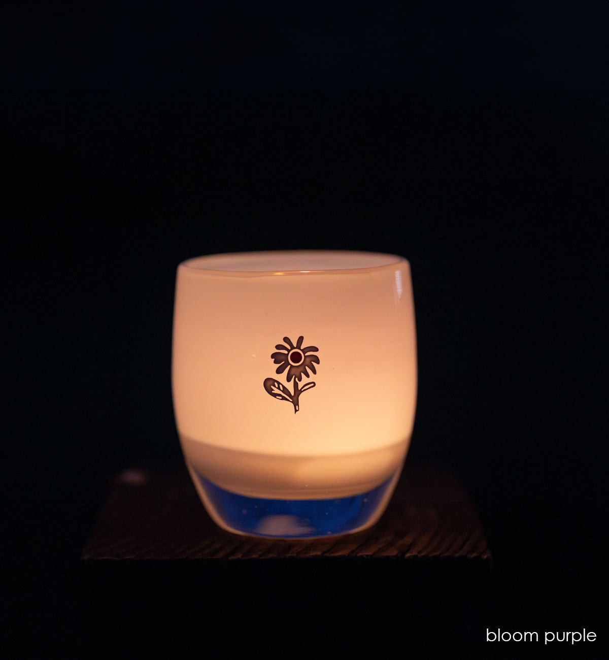 bloom purple glassybaby with white flower etched on it lit at night
