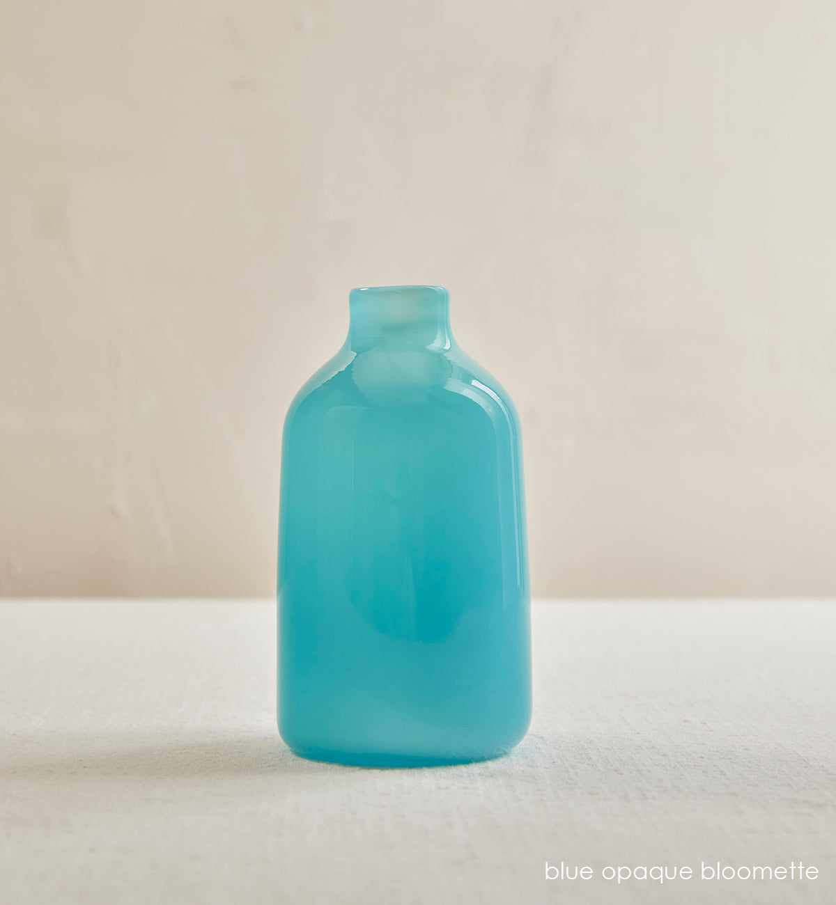 blue opaque bloomette, opaque blue hand-blown glass flower bud vase in a cream room.