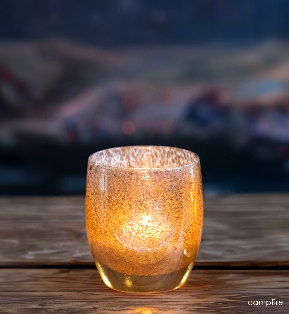 campfire, gold speckled glassybaby, hand-blown glass candle holder on wood bench.