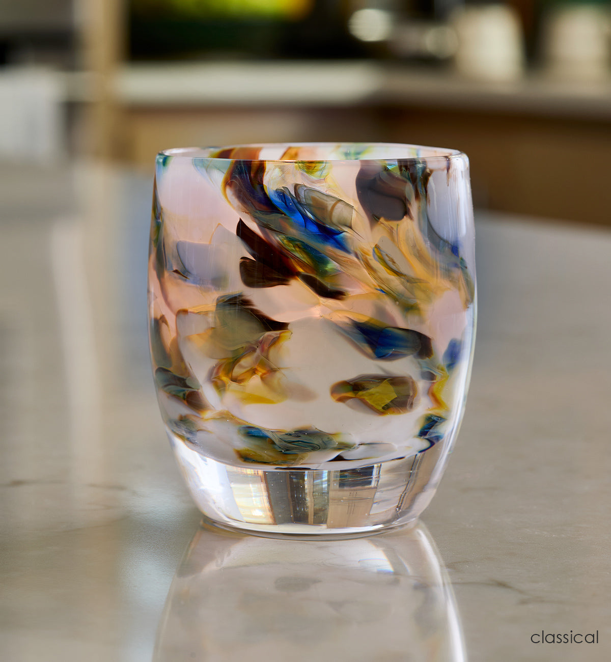 classical, multi-colored blue marble hand-blown glass votive candle holder on a reflective marble kitchen counter.