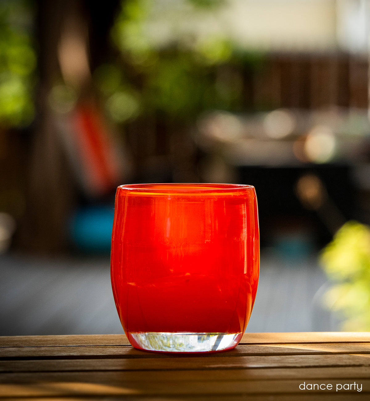 dance party ginger red, hand-blown glass votive candle holder placed on patio table.