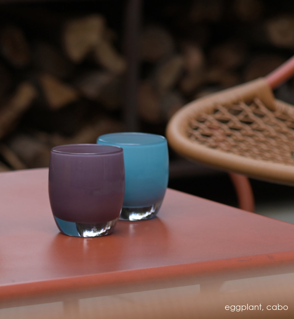 eggplant purple glass hand-blown glass votive candle holder on a red outdoor patio table with cabo.
