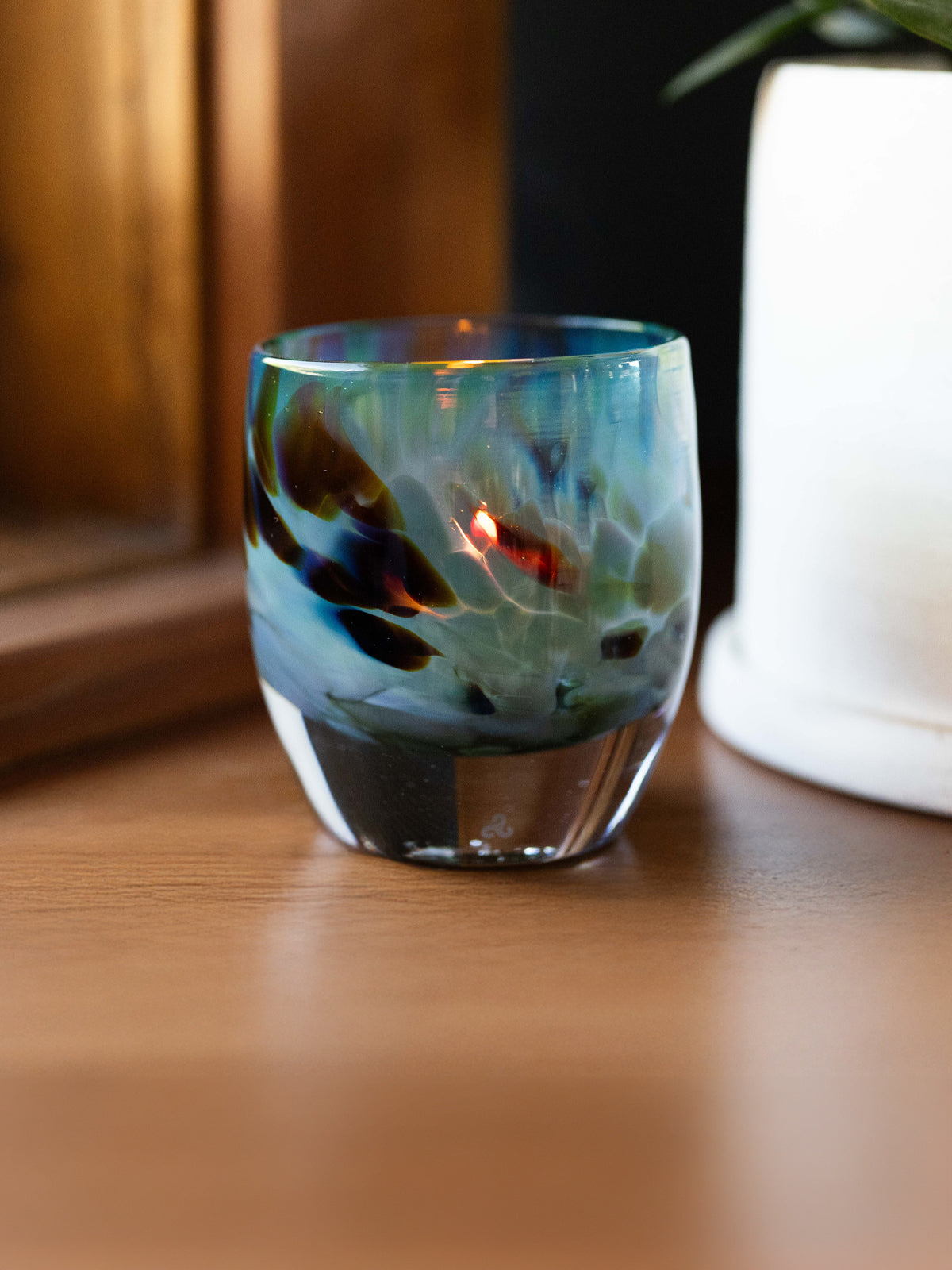 equinox glassybaby, teal and brown hand-blown glass candle holder sitting on table by window