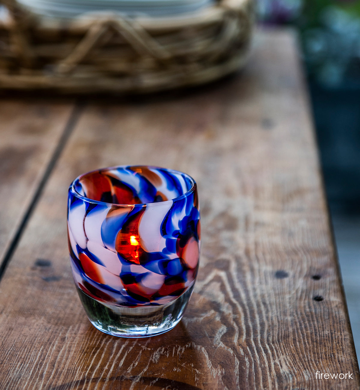 firework, red white and blue petal, hand-blown glass votive candle holder on brown wood picnic table.