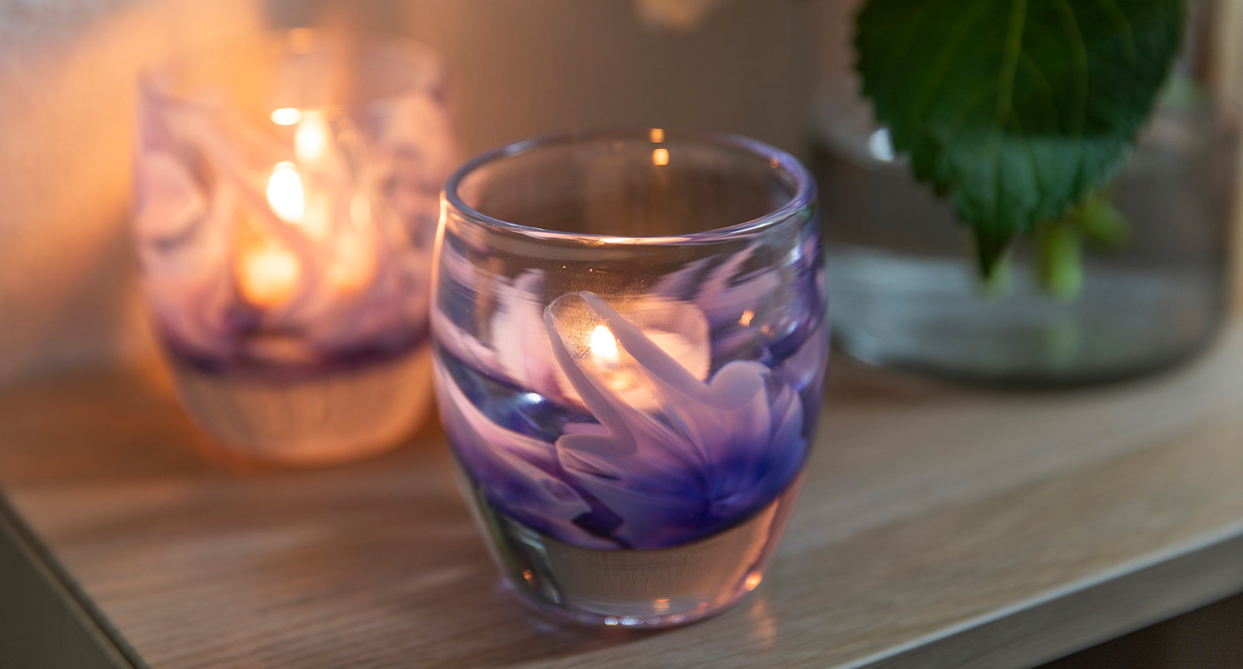 purple murrini flowers on a clear hand-blown class candle holder. flowers for loved ones that will last forever.