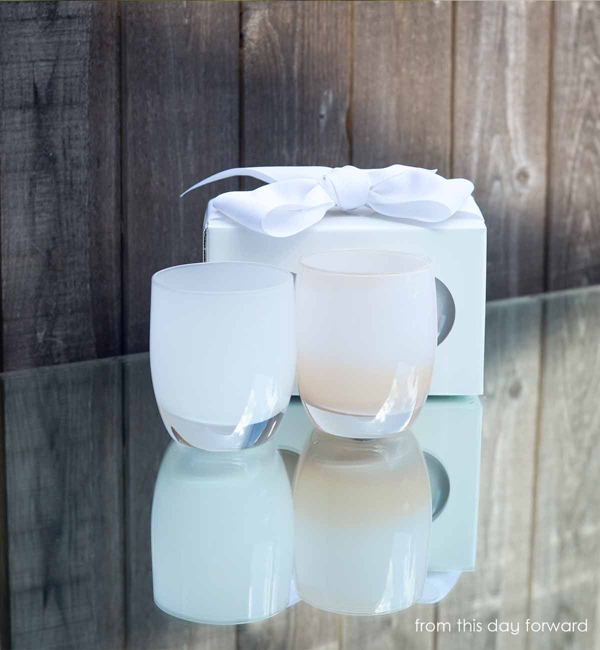 from this day forward set, true white off white, cherish white, hand-blown glass votive candle holders on front of a gift box on a reflective surface in front of wood wall.