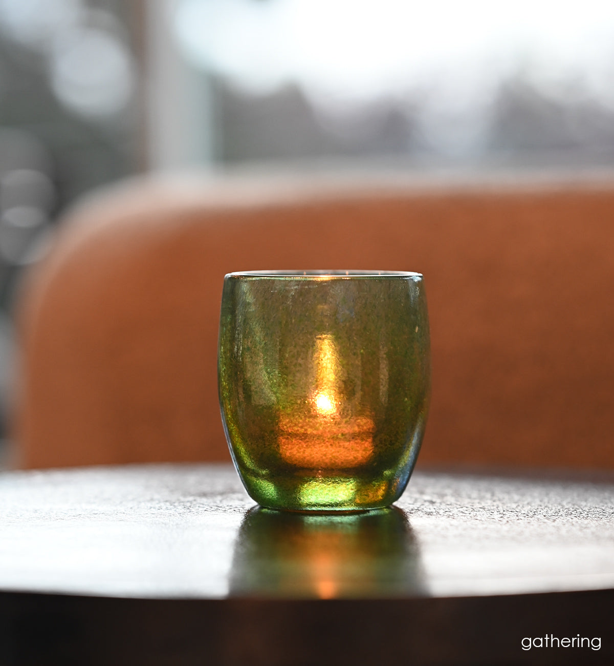 gathering a vibrant shimmering green hand-blown glass candle holder.
