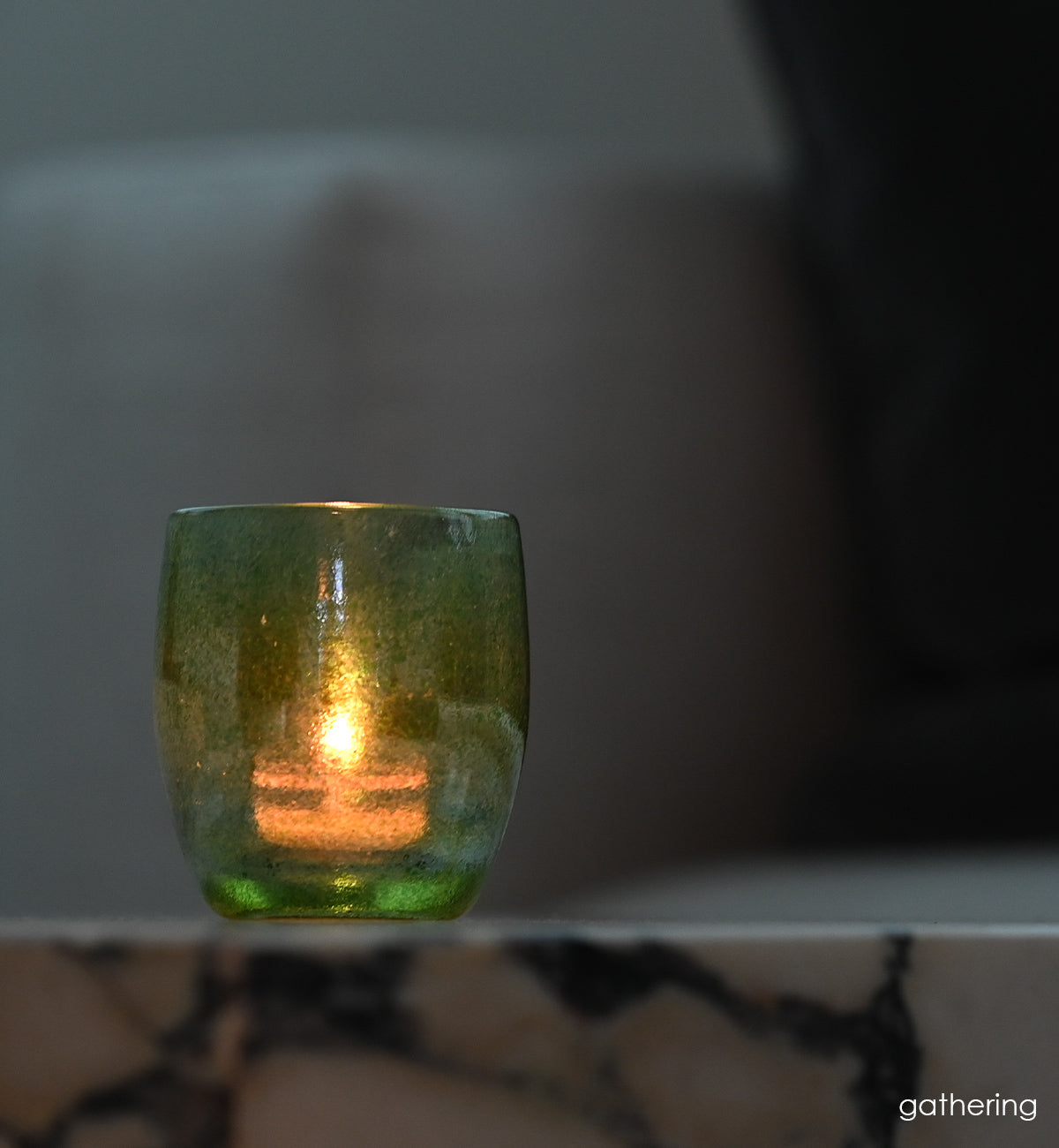gathering, a vibrant shimmering green, hand-blown glass votive candle holder.