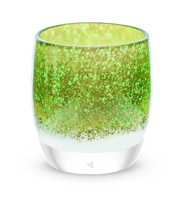 hand-blown glass candle holder with green and gold tones cover a white base. 