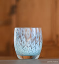 good choice light blue bubble, hand-blown glass votive candle holder on a wood counter.