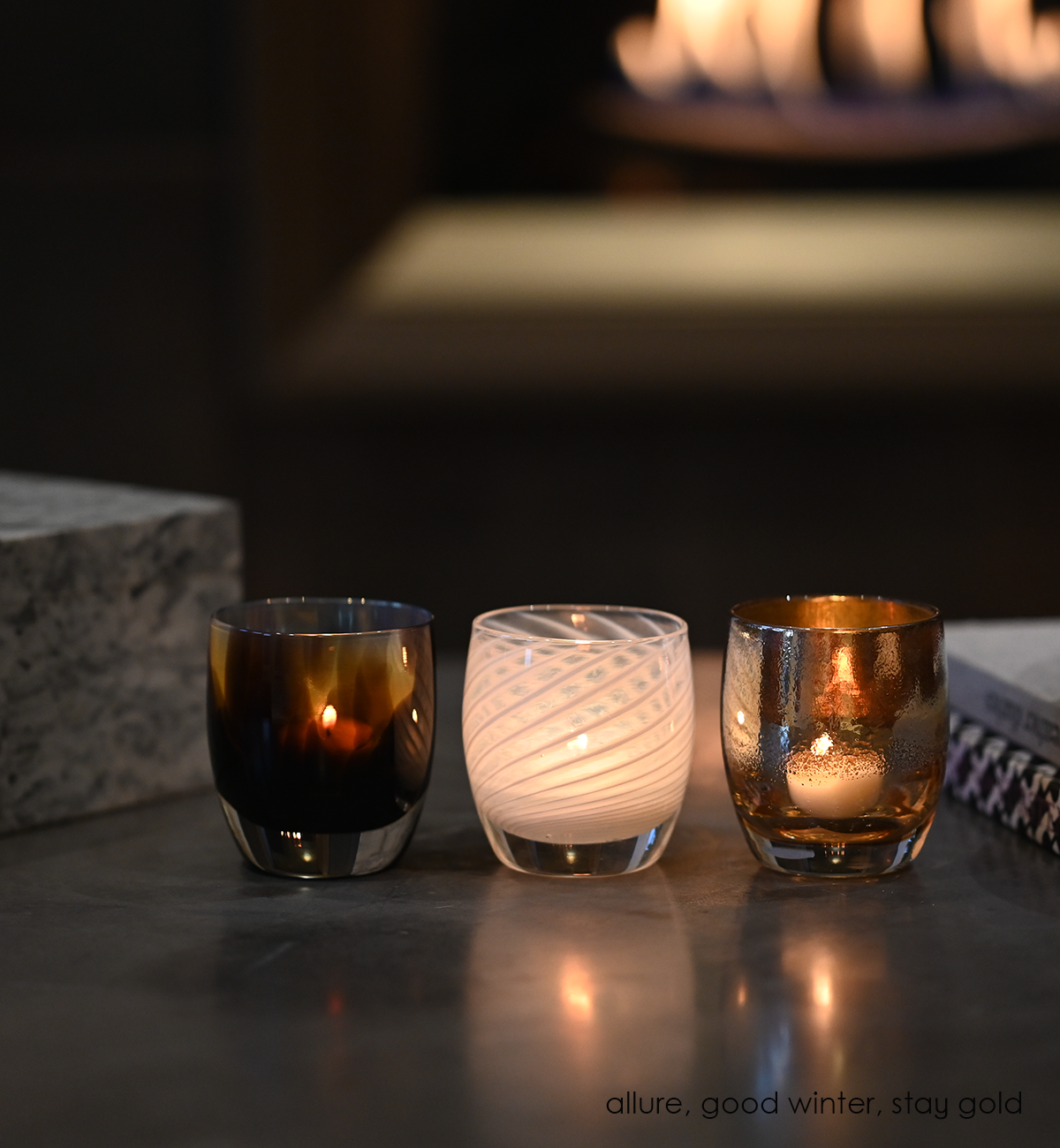 good winter white translucent swirl hand-blown glass votive candle holder with allue and stay gold on a marble coffee table.