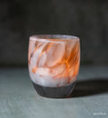 white and brown petal, hand-blown glass votive candle holder when lit gives off an orange glow