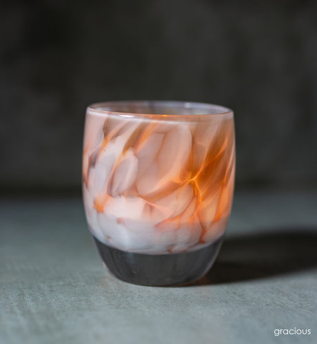 white and brown petal, hand-blown glass votive candle holder when lit gives off an orange glow