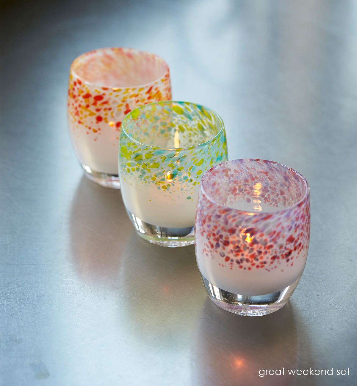 great weekend set spring colors topping hand-blown glass votive candle holders on a metal table.