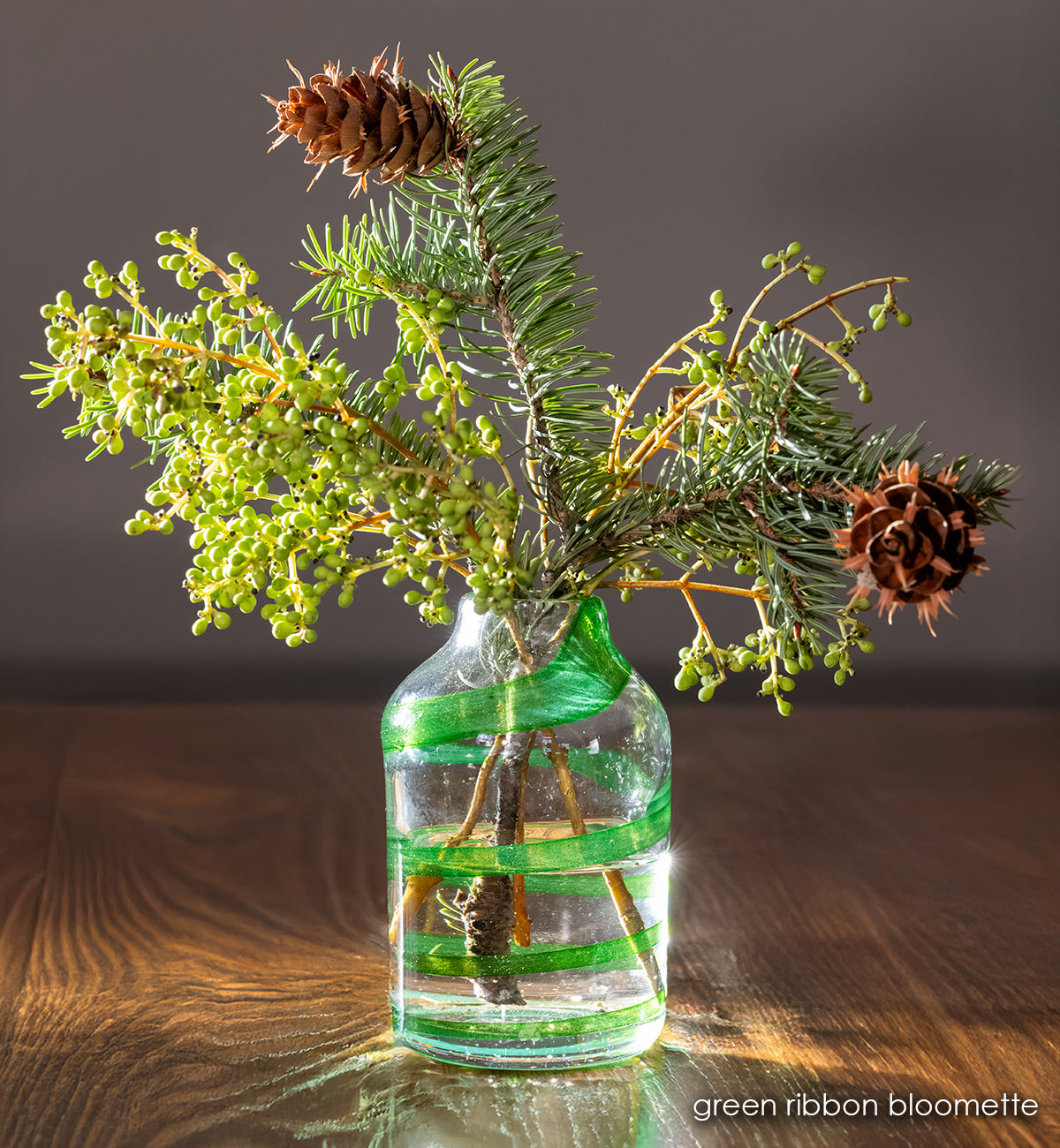 clear handblown glass bloomette with green twisted around it. with green flowers in vase. 