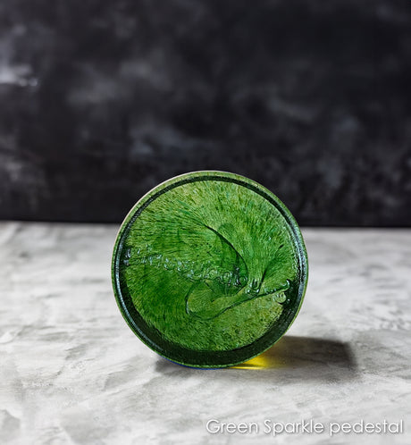 Green sparkling pedestal on a gray surface with a dark background