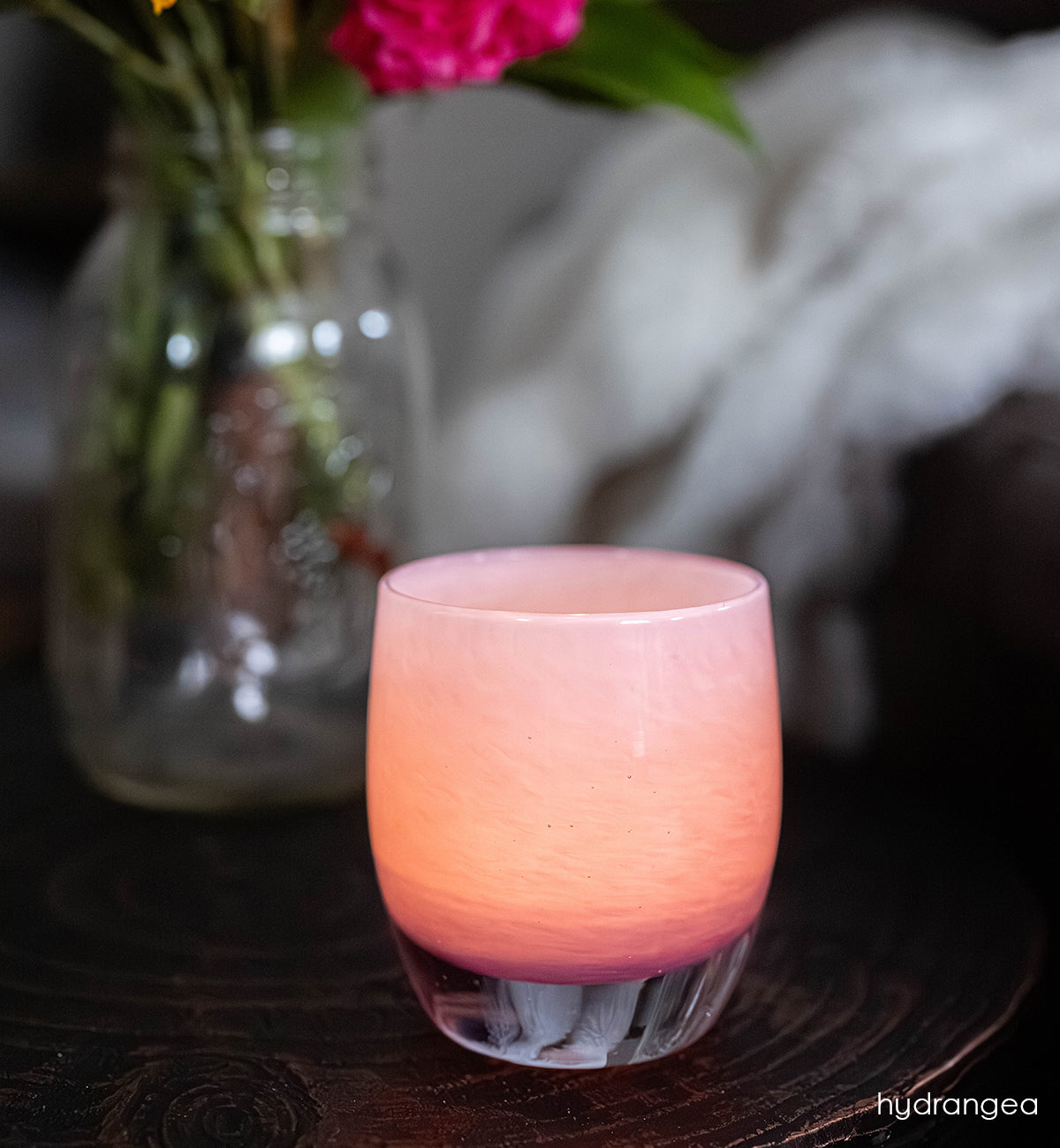 hydrangea | pink with purple ombré hand-blown glass candle holder on a dark surface with a blurred background