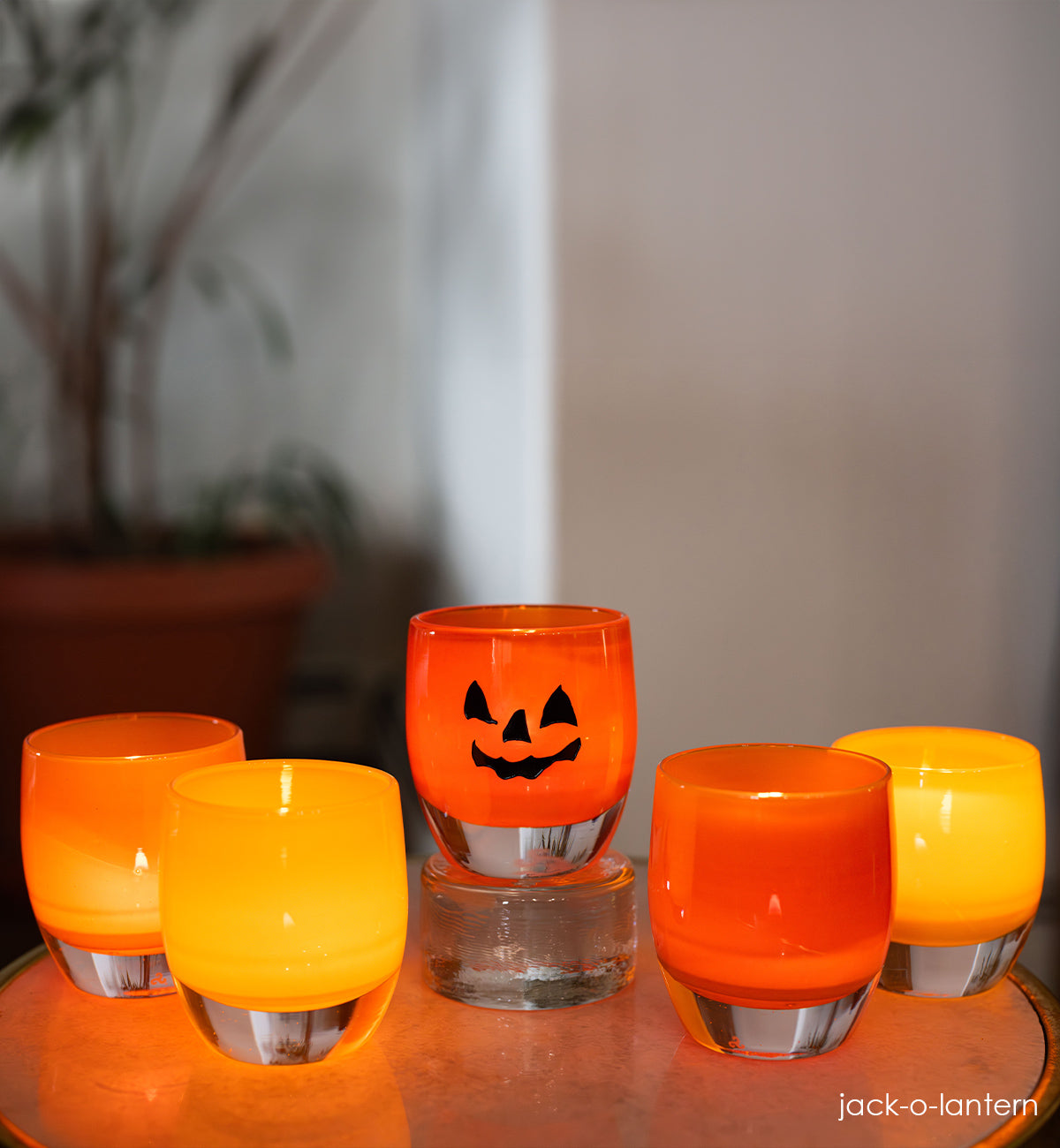 jack-o-lantern, orange hand-blown glass votive candle holder with a spooky jack-o-lantern face hand-etched in black fill.