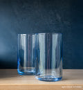 light blue tumbler on butcher block with blue background