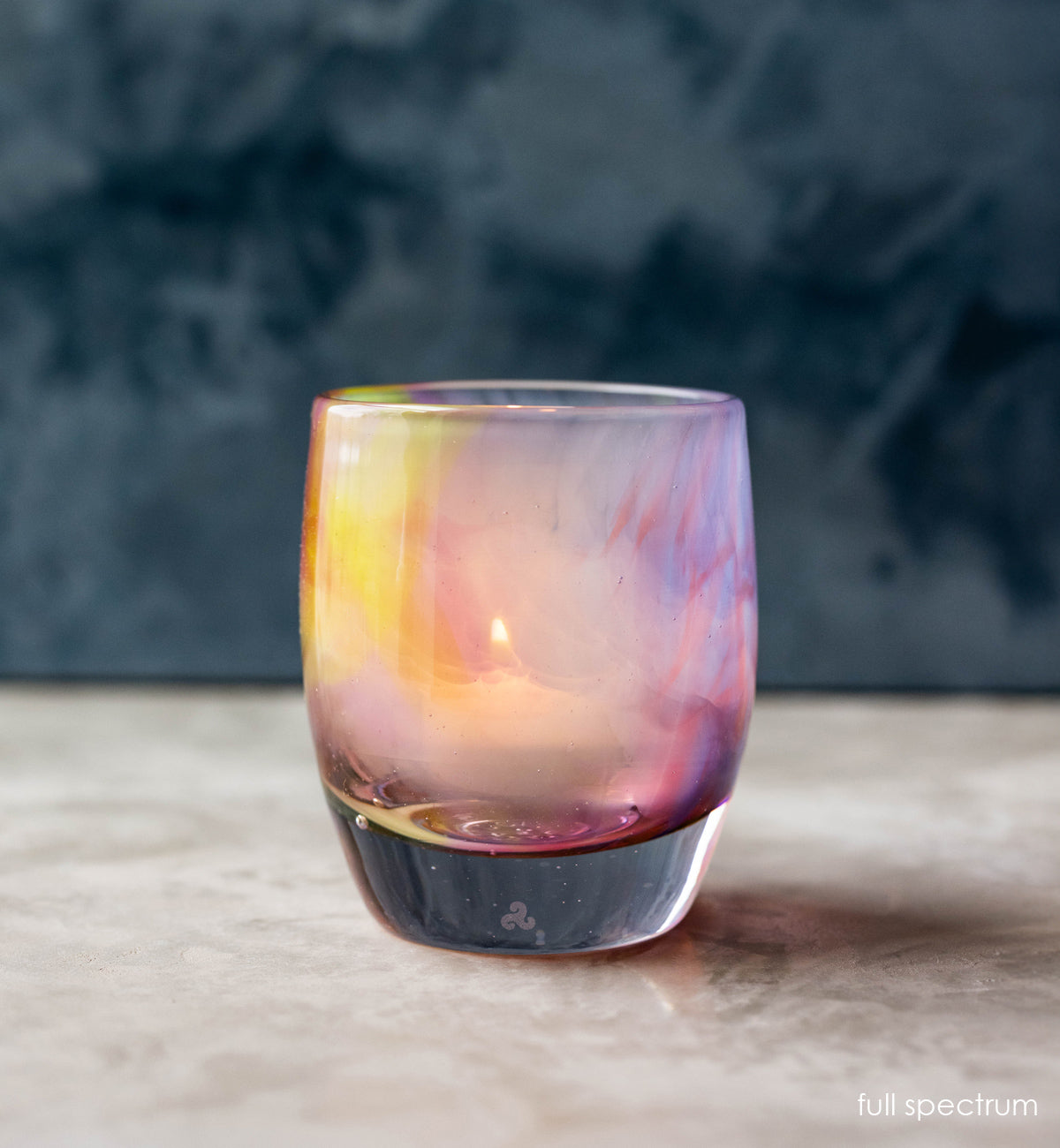 A multicolored glass candle holder with a design that resembles a rainbow 