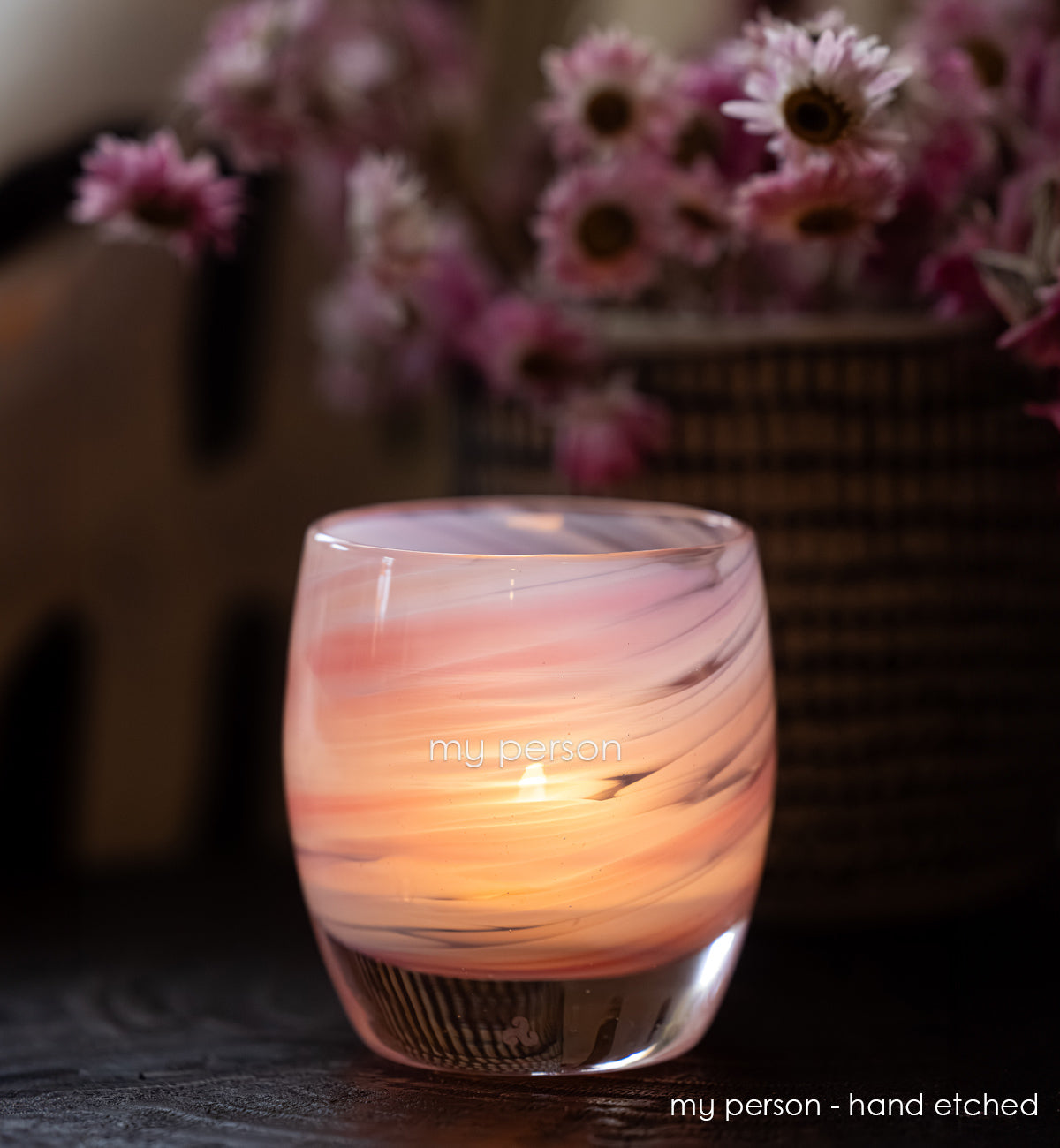 Glass candle holder with marbled design and 'my person' hand etched on a blurred background