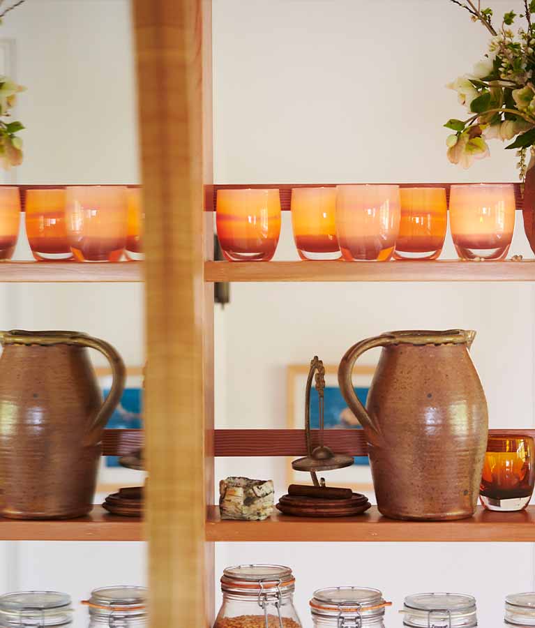 nurture, warm peachy with purple banding, hand-blown glass votive candle holder lined up on a shelf