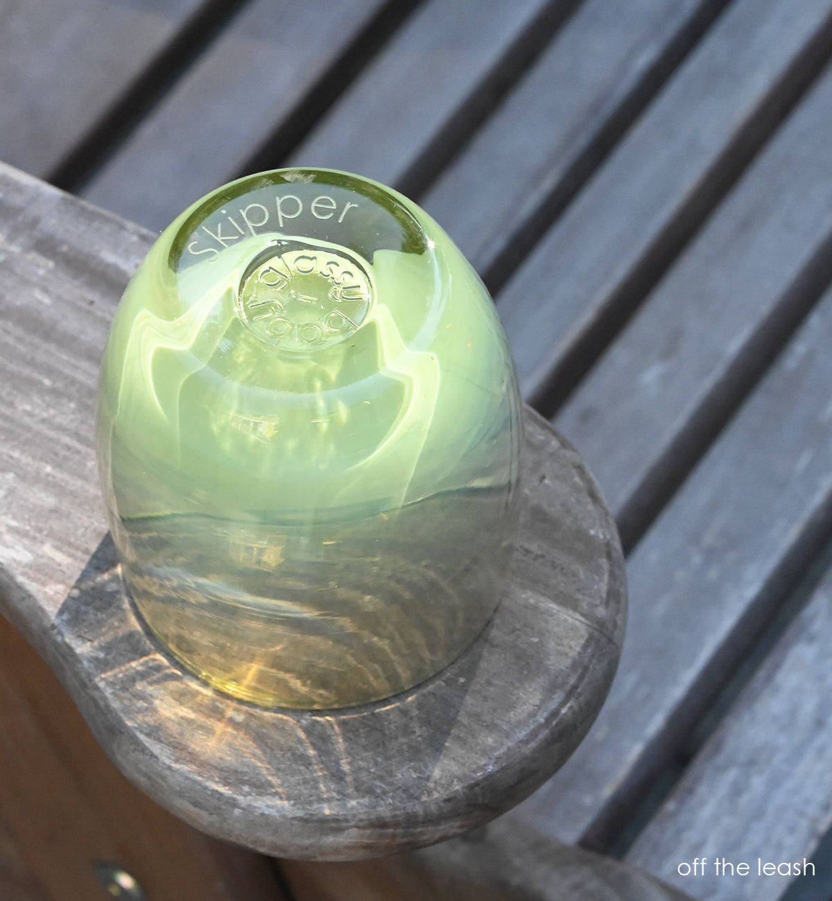 off the leash is a moss green hand-blown glass votive candle holder. transparent towards the top. bottom etched with "skipper"