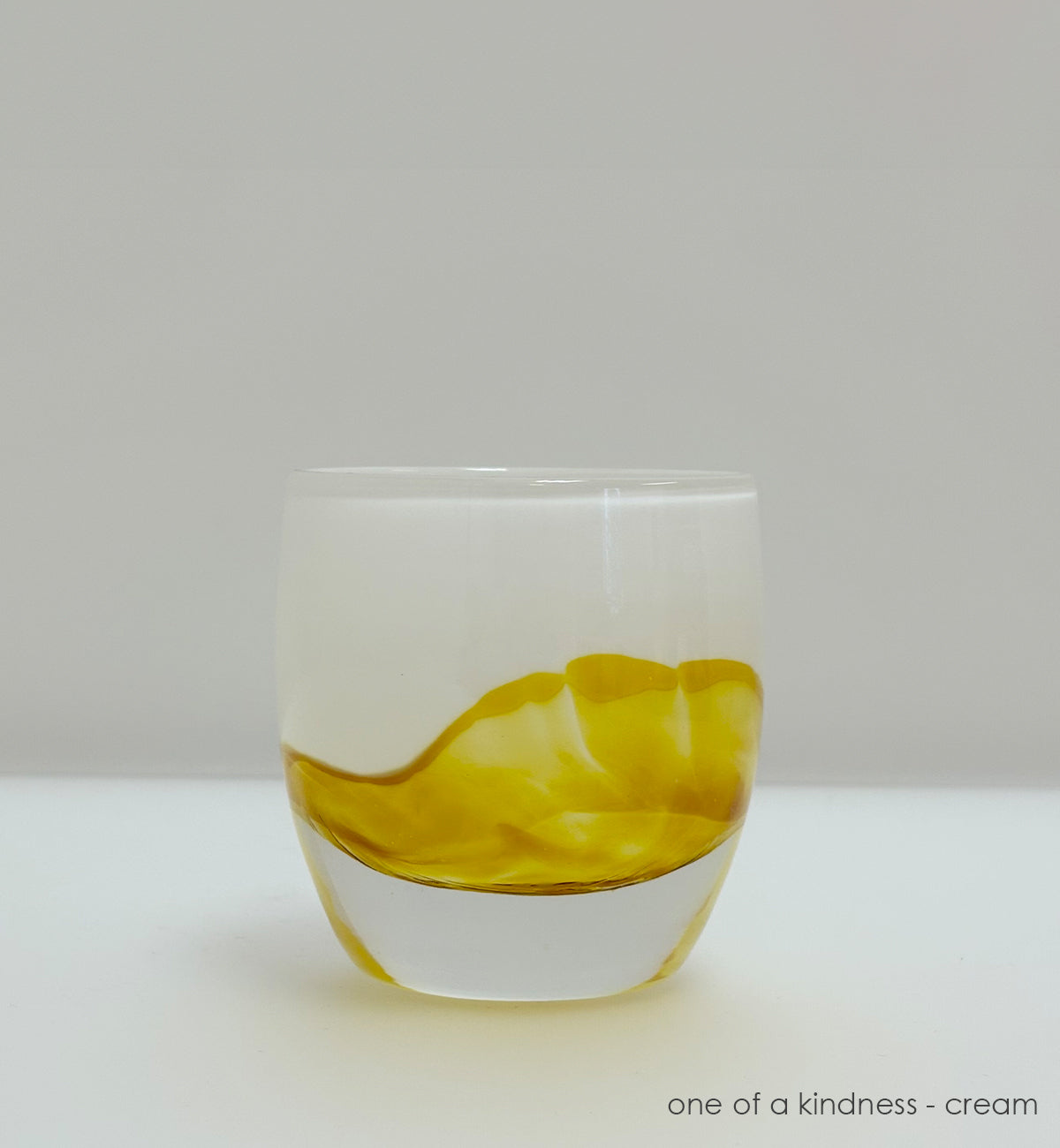 yellow and cream coloration glass candle holder  on a gray background