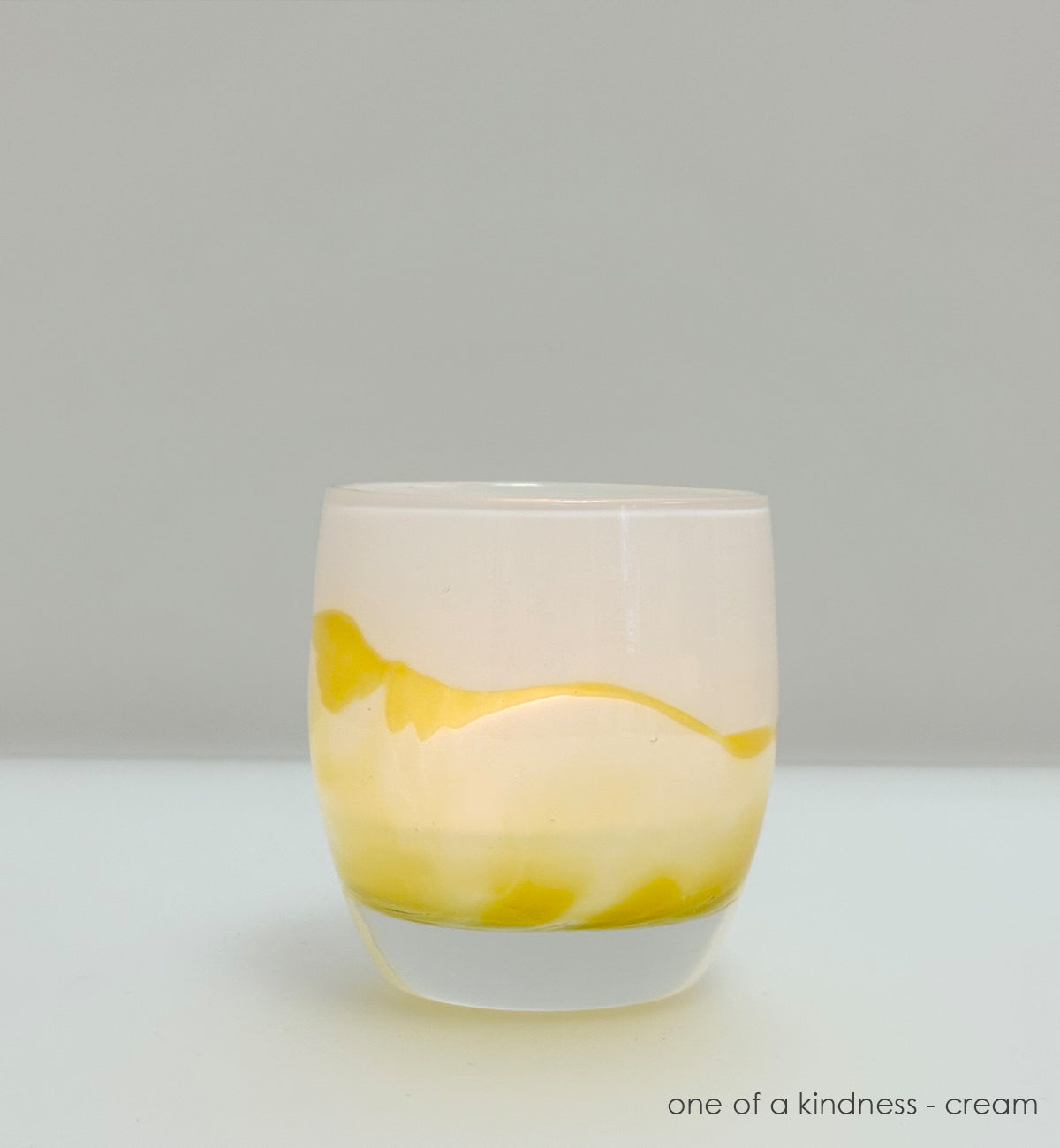 yellow and cream coloration glass candle holder  on a gray background
