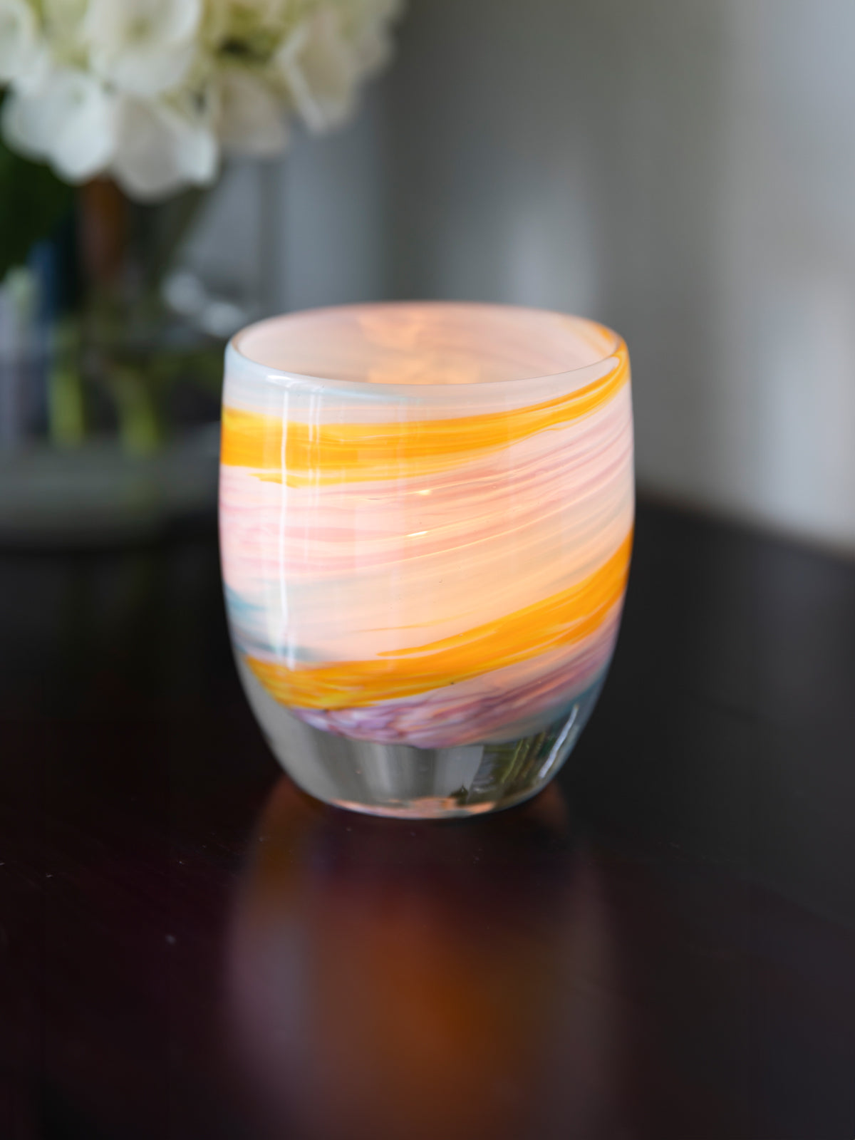places you'll go hand-blown multi-colored yellow, white, blue, purple swirl hand-blown glass votive candle holder set on a dark brown wood table.