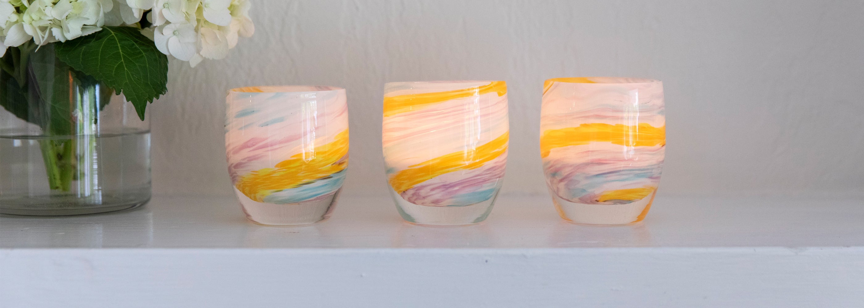 places you'll go hand-blown multi-colored yellow, white, blue, purple swirl hand-blown glass votive candle holder set on a white mantel.