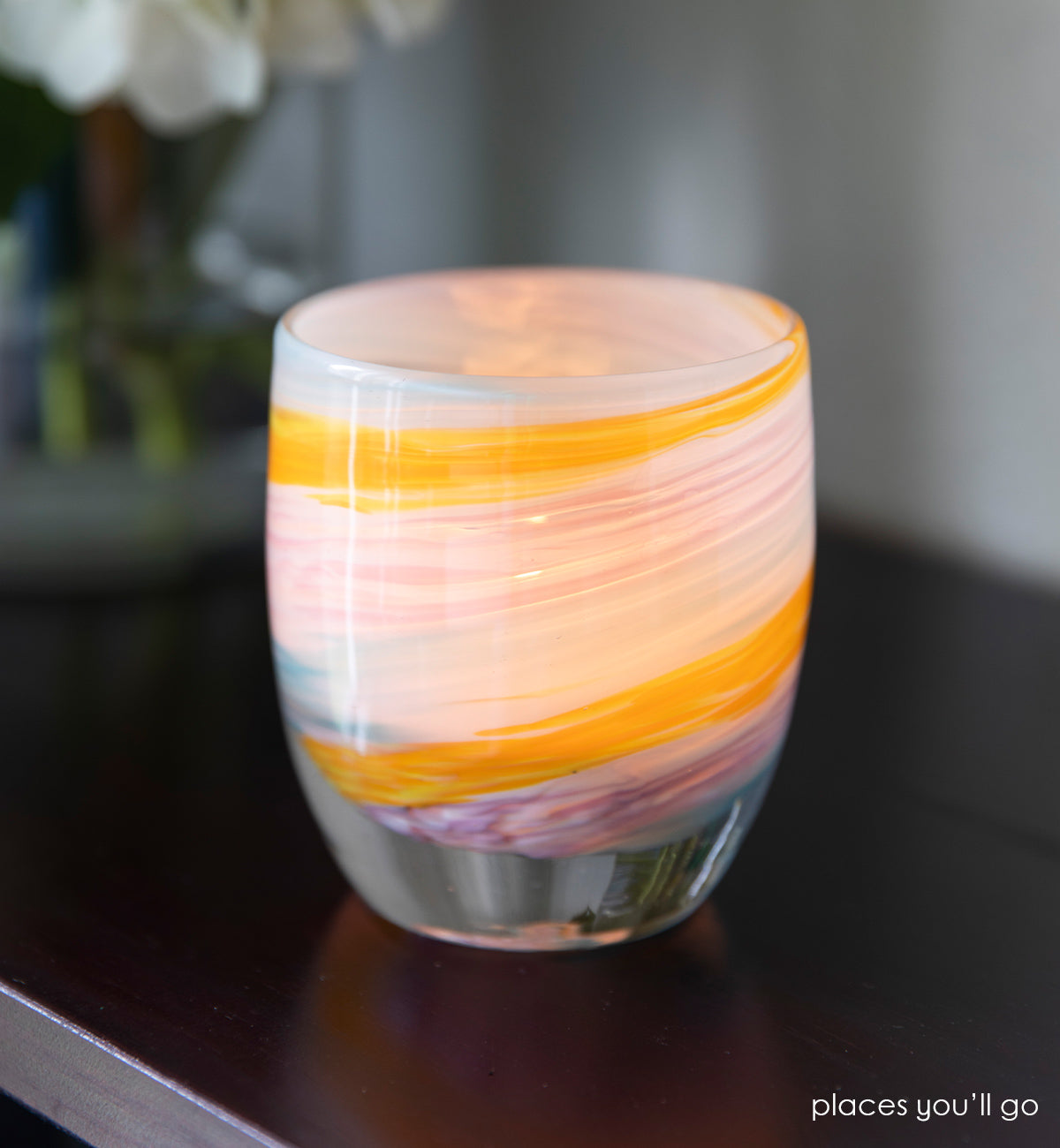 places you'll go hand-blown multi-colored yellow, white, blue, purple swirl hand-blown glass votive candle holder set on a dark brown wood table.