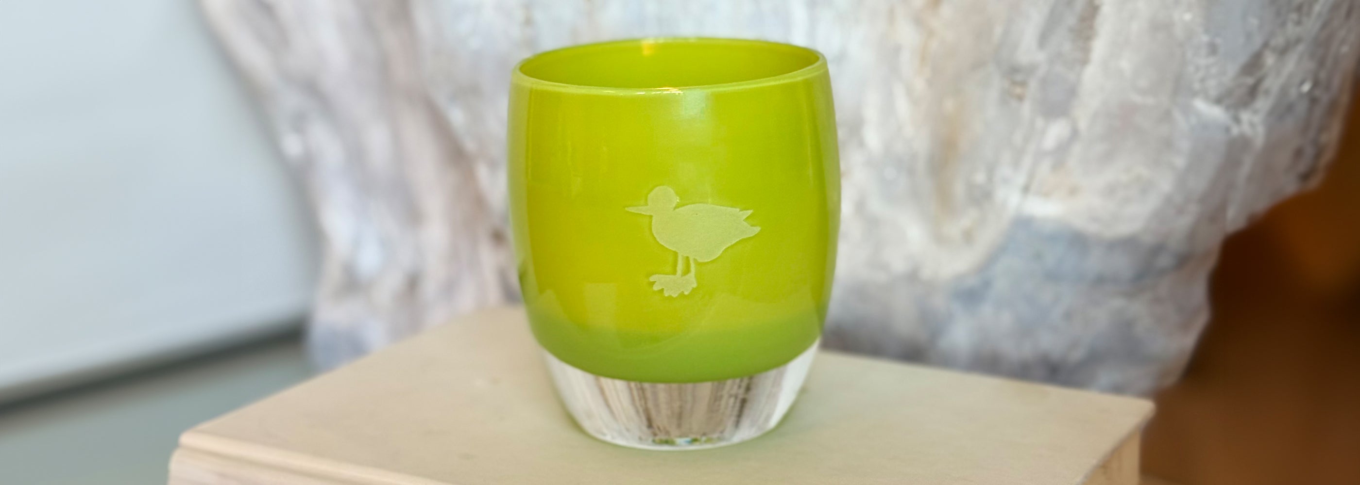 green glass candle holder with hand etched seagull on white surface