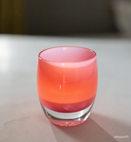 smooch bright pink hand blown glass candle holder on white surface.