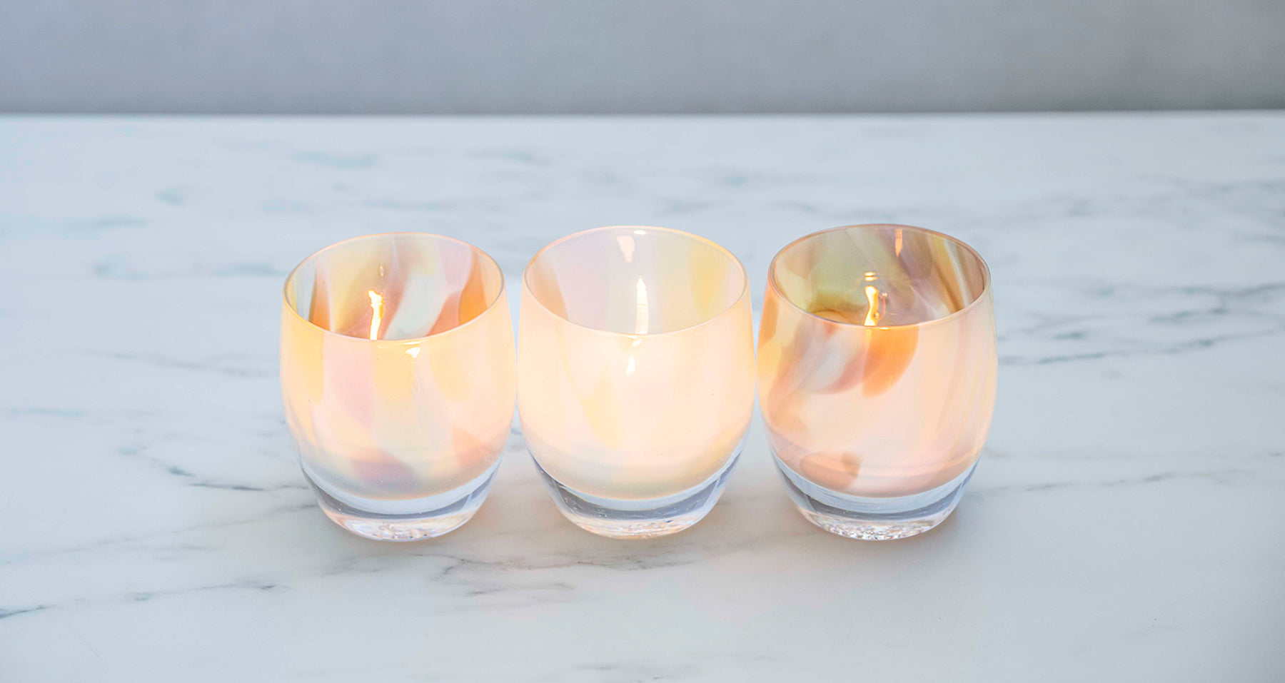pastel colors collide in so much fun, a hand-blown glass candle holder perfect for mother's day, resting on a marble table.
